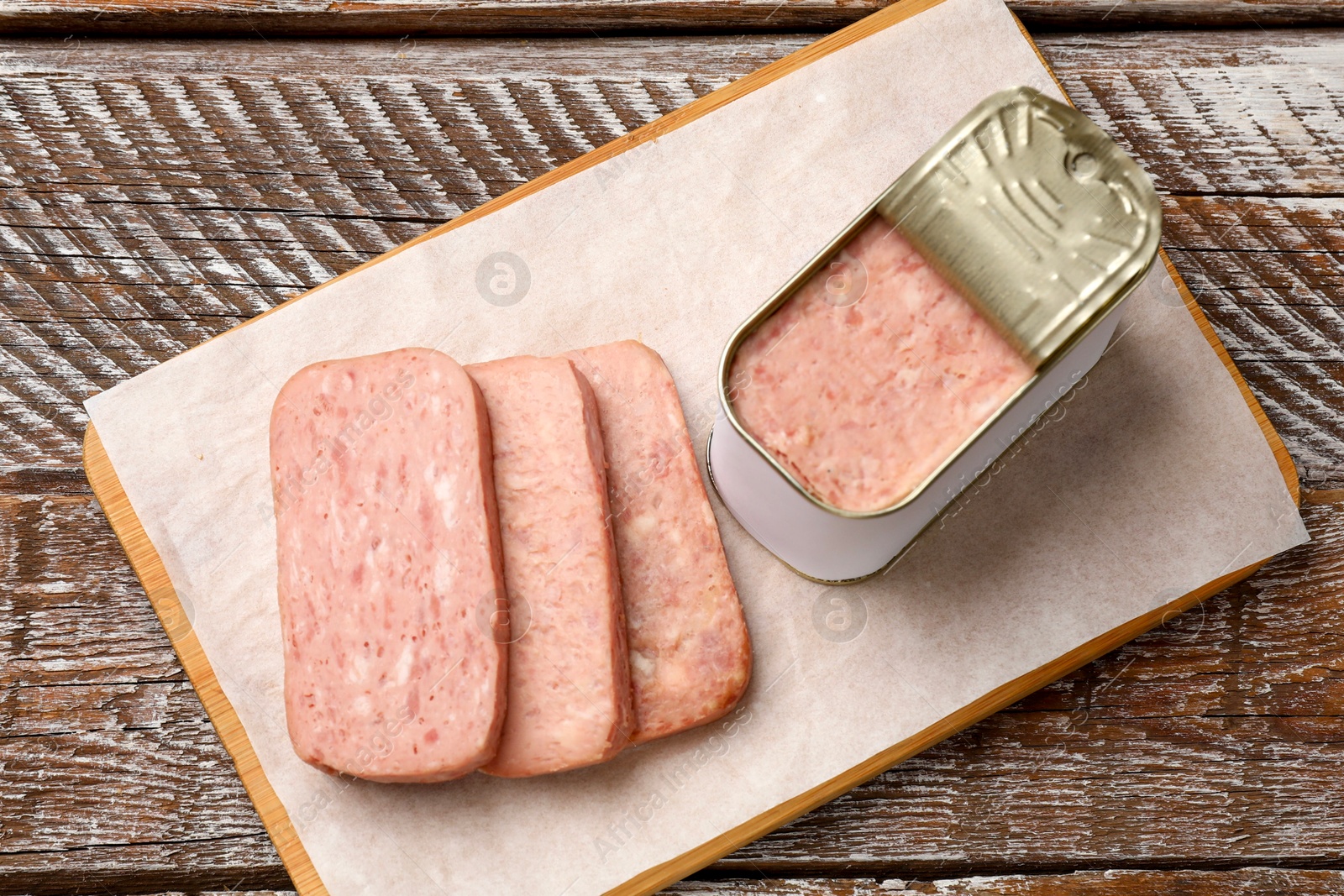 Photo of Canned meat in tin can on wooden table, top view