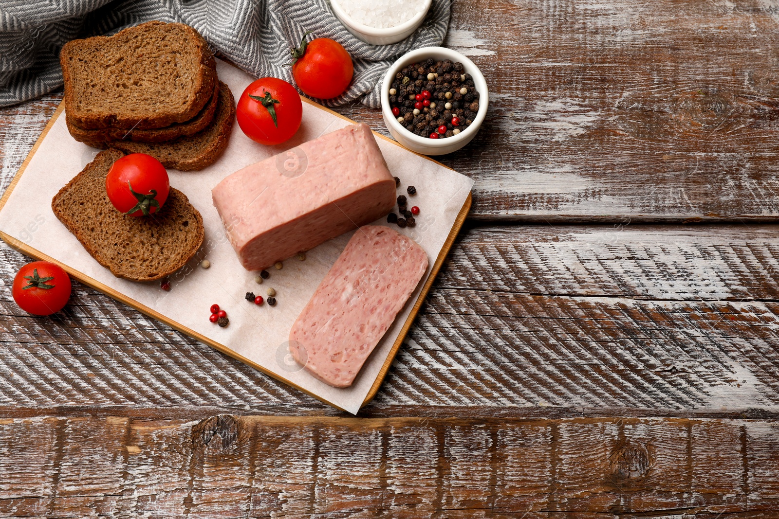 Photo of Canned meat, spices, tomatoes and bread on wooden table, flat lay. Space for text