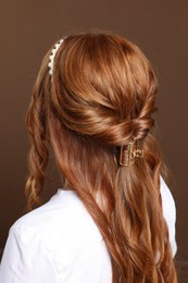 Photo of Teenage girl with stylish hair accessories on brown background, back view