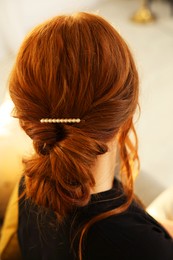 Photo of Teenage girl with stylish hair clip indoors, back view