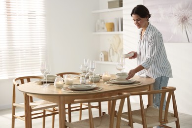 Photo of Woman setting table for dinner at home