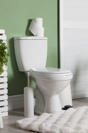 Photo of Ceramic toilet bowl, necessities and folding screen in restroom