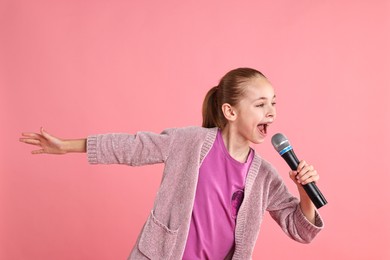 Photo of Little girl with microphone singing on pink background