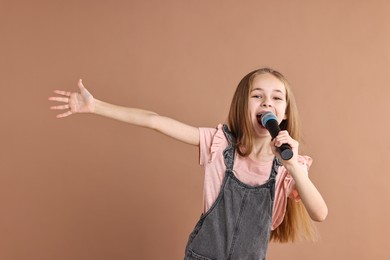 Photo of Little girl with microphone singing on light brown background