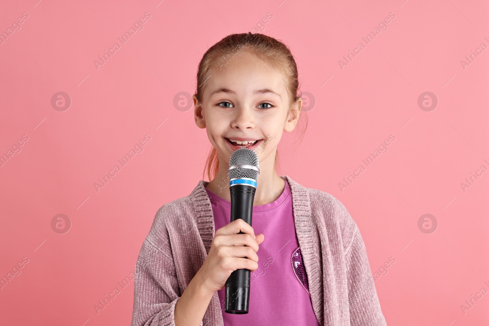 Photo of Little girl with microphone on pink background