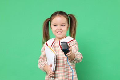 Photo of Smiling girl with microphone and notebook on green background