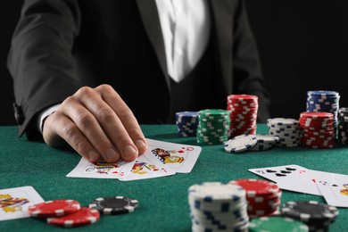 Man with cards and casino chips playing poker at gambling table, closeup