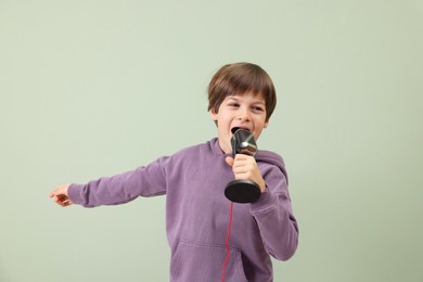 Photo of Cute boy with microphone singing near green wall