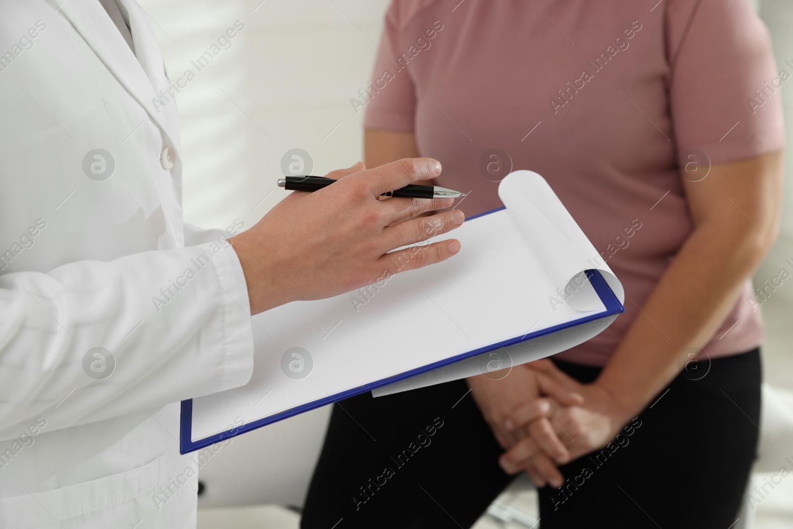 Photo of Nutritionist with clipboard giving recommendations to overweight woman in hospital, closeup