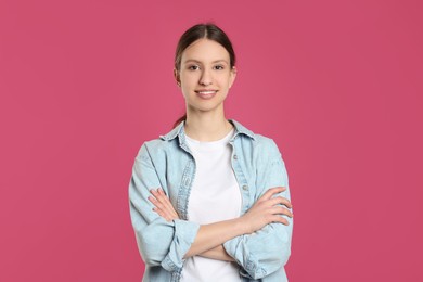 Photo of Portrait of smiling teenage girl with crossed arms on pink background