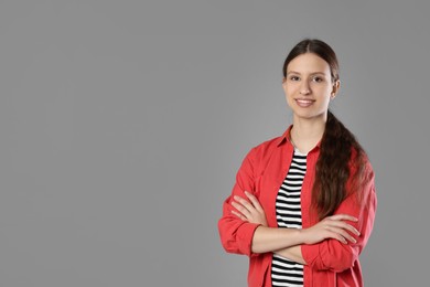 Photo of Portrait of smiling teenage girl with crossed arms on grey background. Space for text