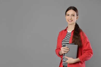 Photo of Portrait of smiling teenage girl with books on grey background. Space for text