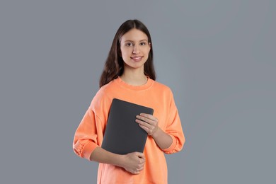 Photo of Portrait of smiling teenage girl with laptop on grey background