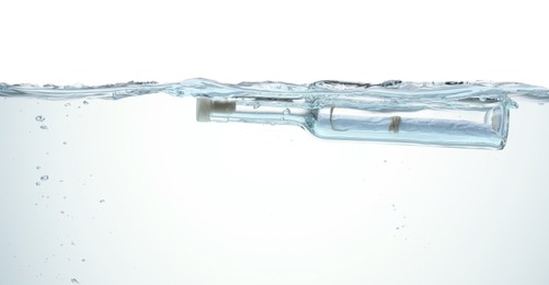 Photo of Corked glass bottle with rolled letter in water on white background