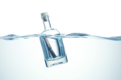 Photo of Corked glass bottle with rolled letter in water on white background