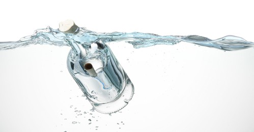 Photo of Corked glass bottle with rolled letter in water on white background