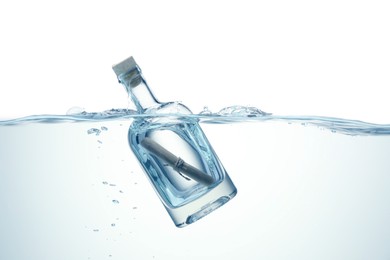 Photo of Corked glass bottle with rolled letter in water on white background