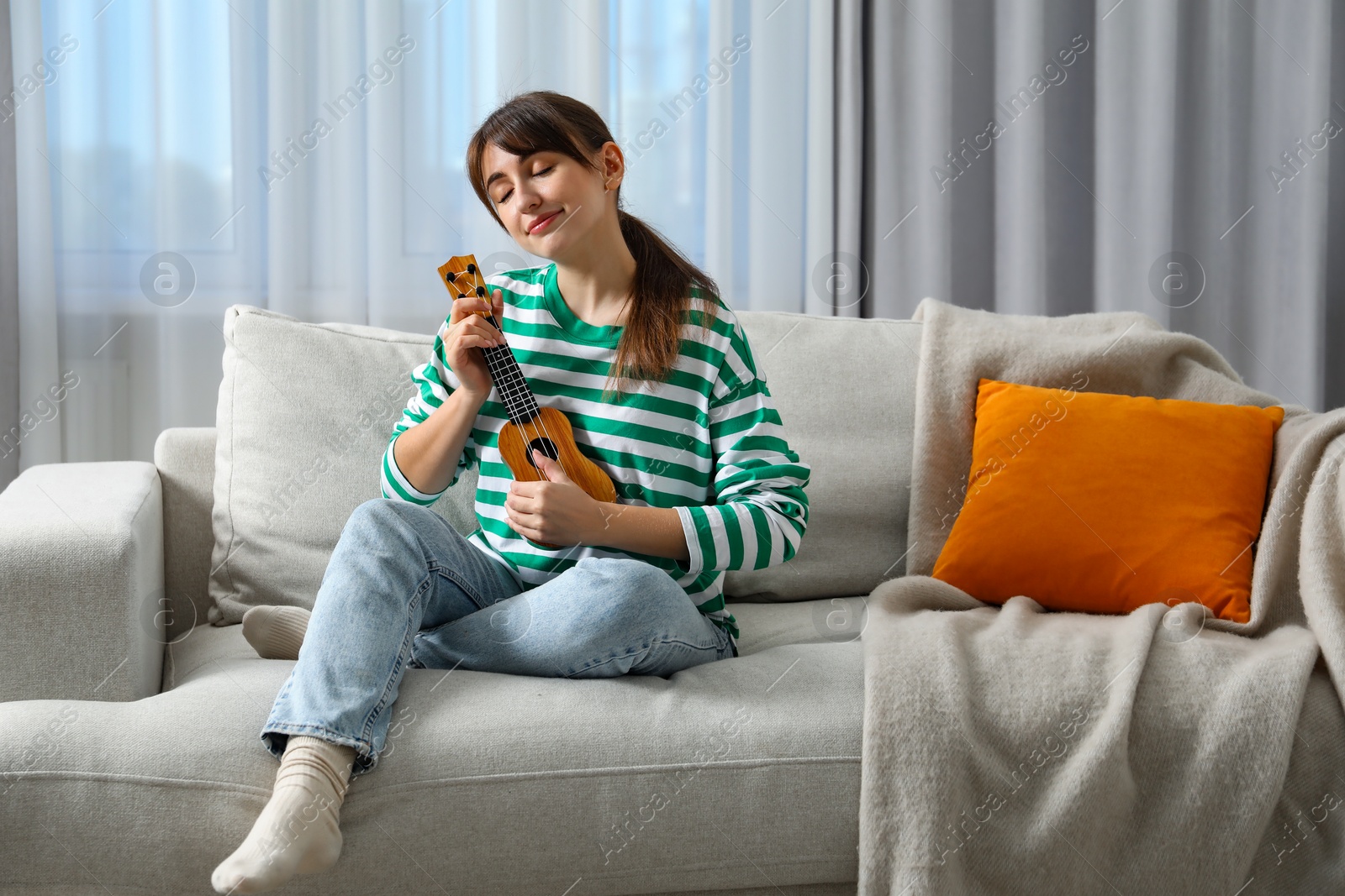 Photo of Woman playing ukulele on sofa at home