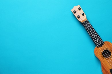 Photo of One ukulele on light blue background, top view. Space for text