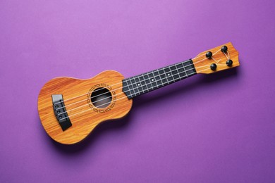 One ukulele on purple background, top view