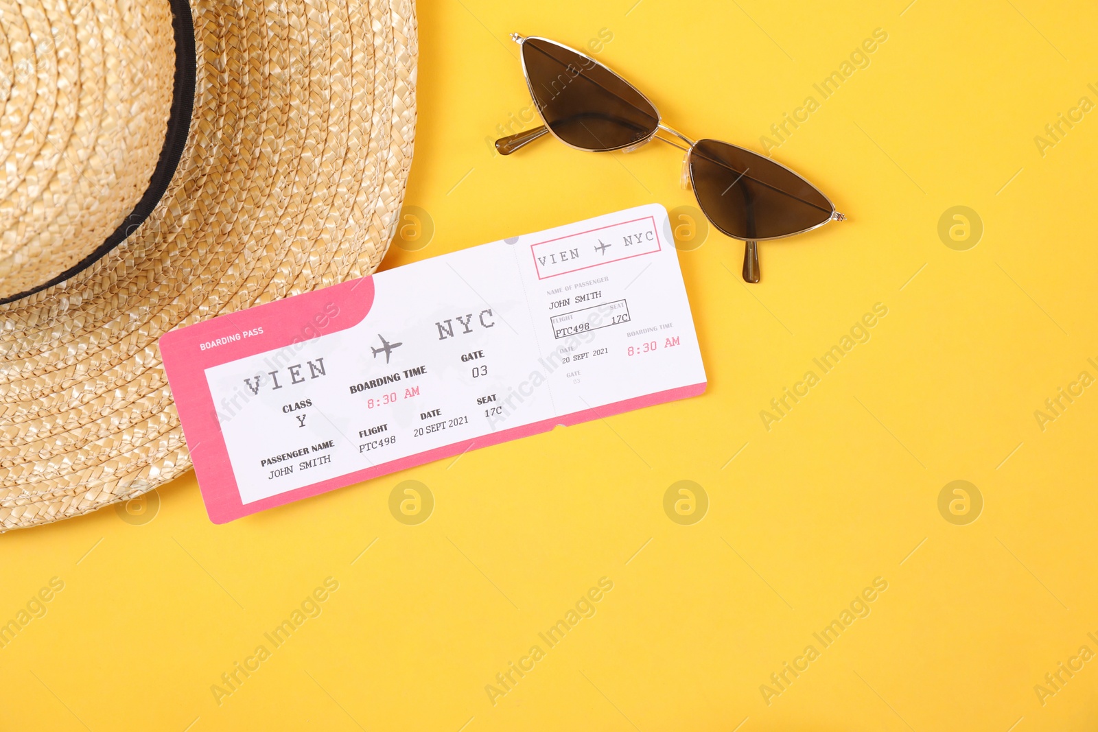 Photo of Airplane ticket, sunglasses and straw hat on yellow background, flat lay. Travel abroad