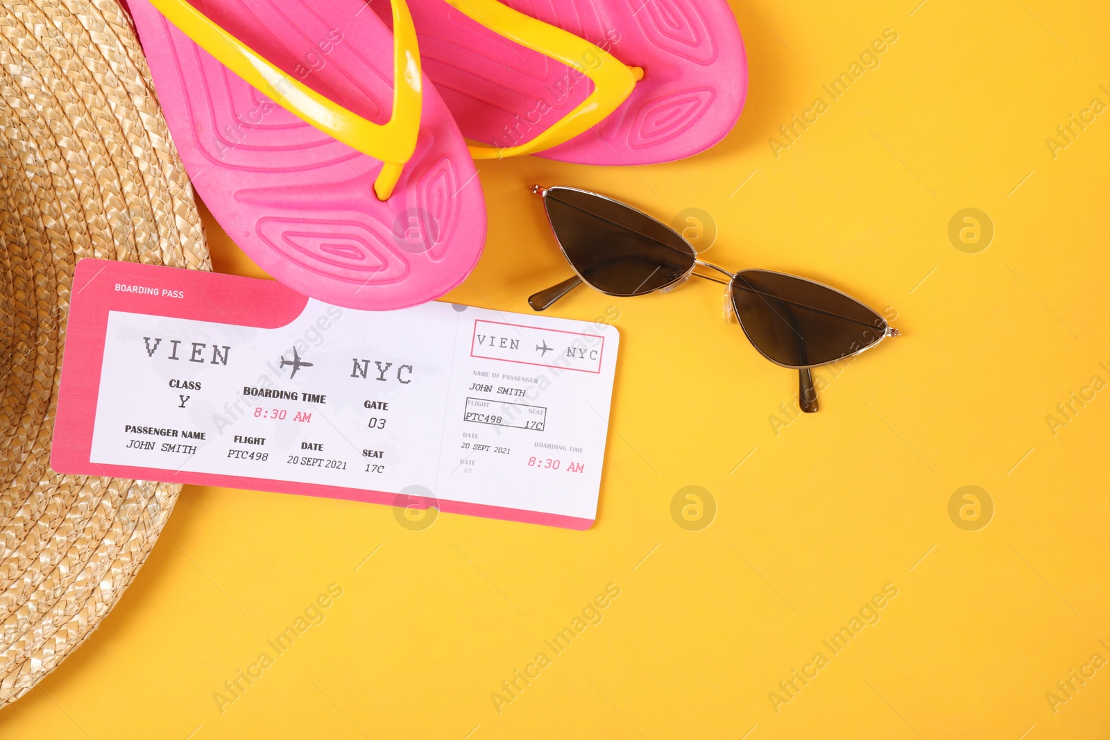 Photo of Airplane ticket, sunglasses, flip flops and straw hat on yellow background, flat lay. Travel abroad