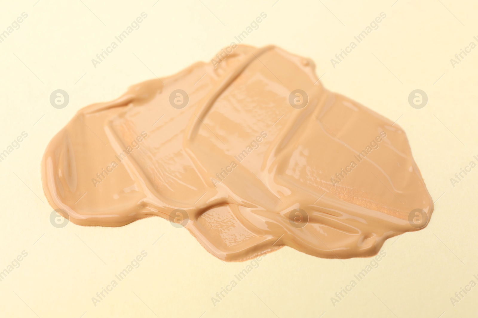 Photo of Sample of foundation on beige background, closeup