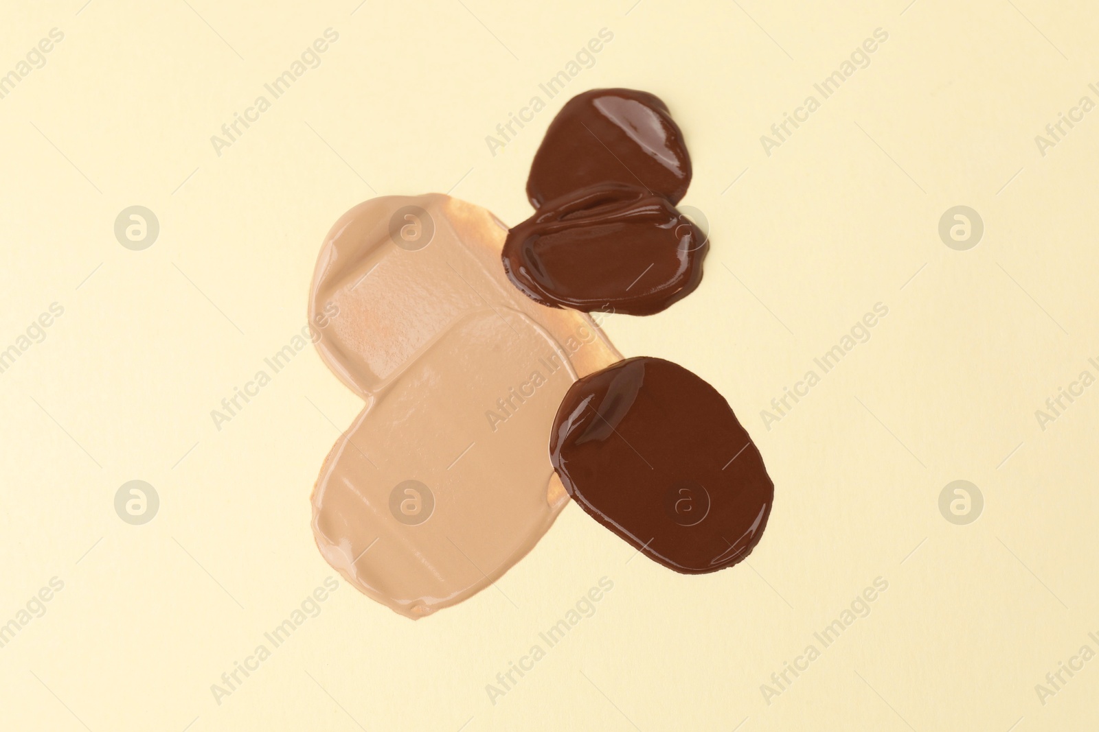 Photo of Samples of different foundations on beige background, above view