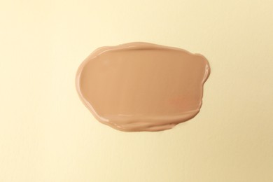 Photo of Sample of foundation on beige background, top view