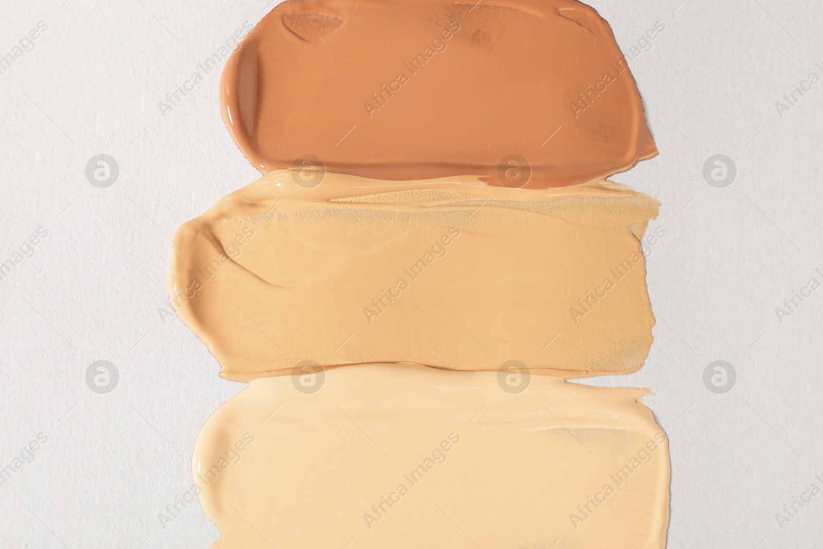 Photo of Samples of different foundation on light grey background, top view