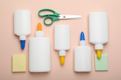 Photo of Bottles of glue, scissors and notes on beige background, flat lay