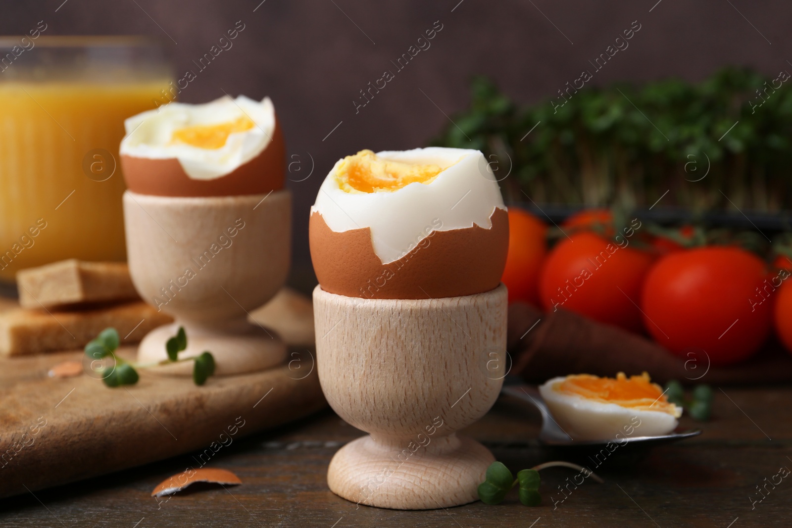 Photo of Soft boiled eggs, microgreens and tomatoes on wooden table, selective focus