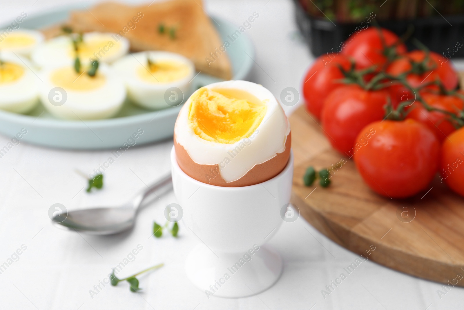 Photo of Soft boiled egg on white tiled table, closeup