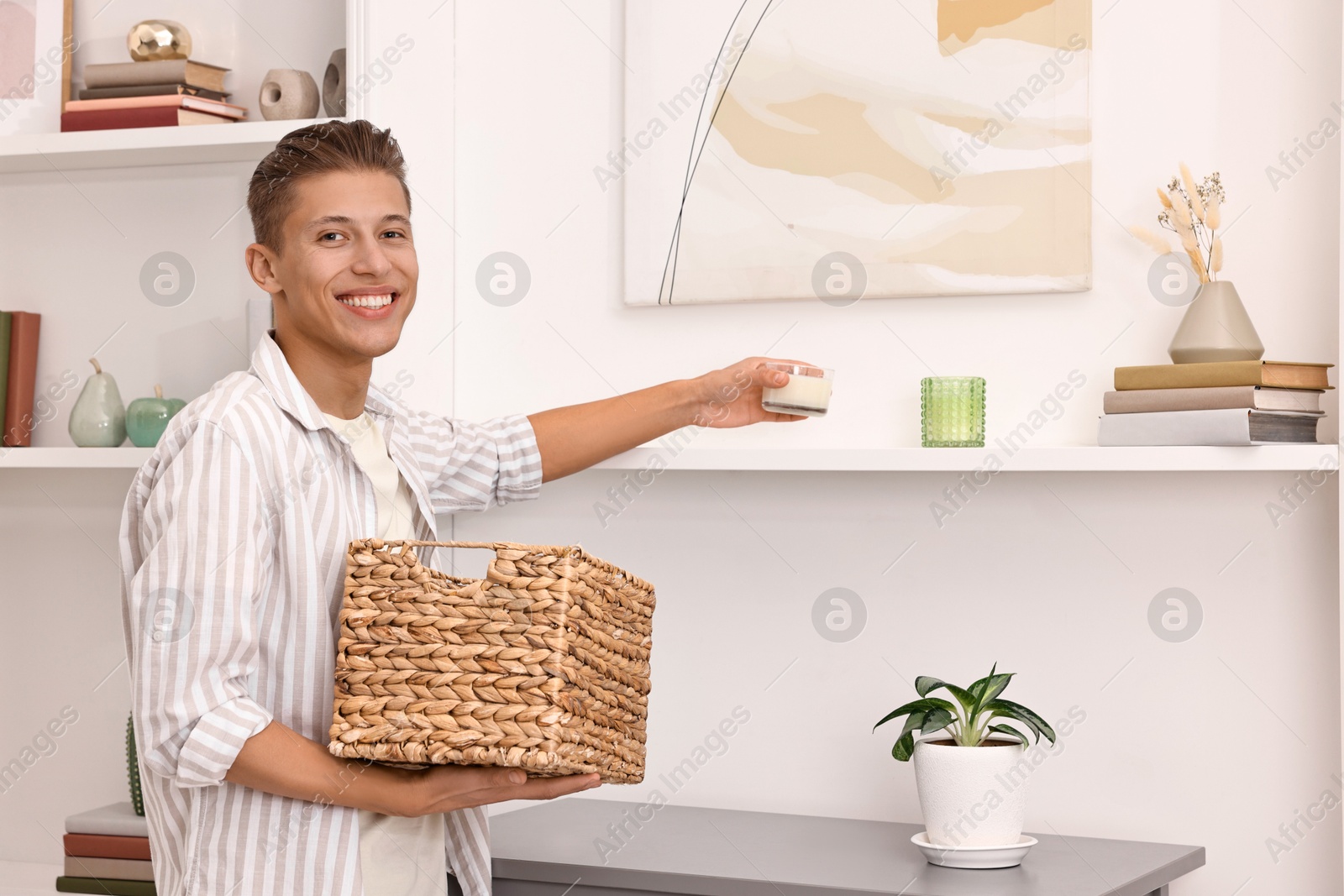 Photo of Smiling decorator arranging decor onto shelf at home