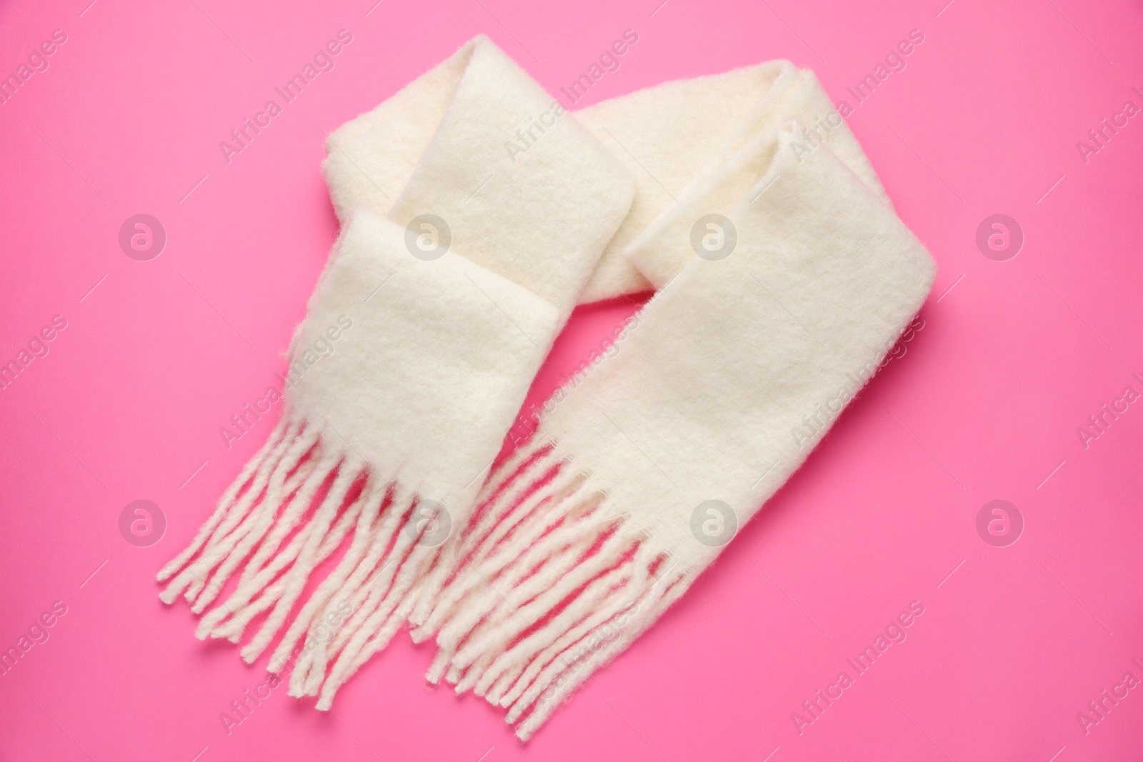 Photo of Warm woolen scarf on pink background, top view