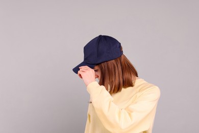 Photo of Woman in stylish baseball cap on grey background. Mockup for design