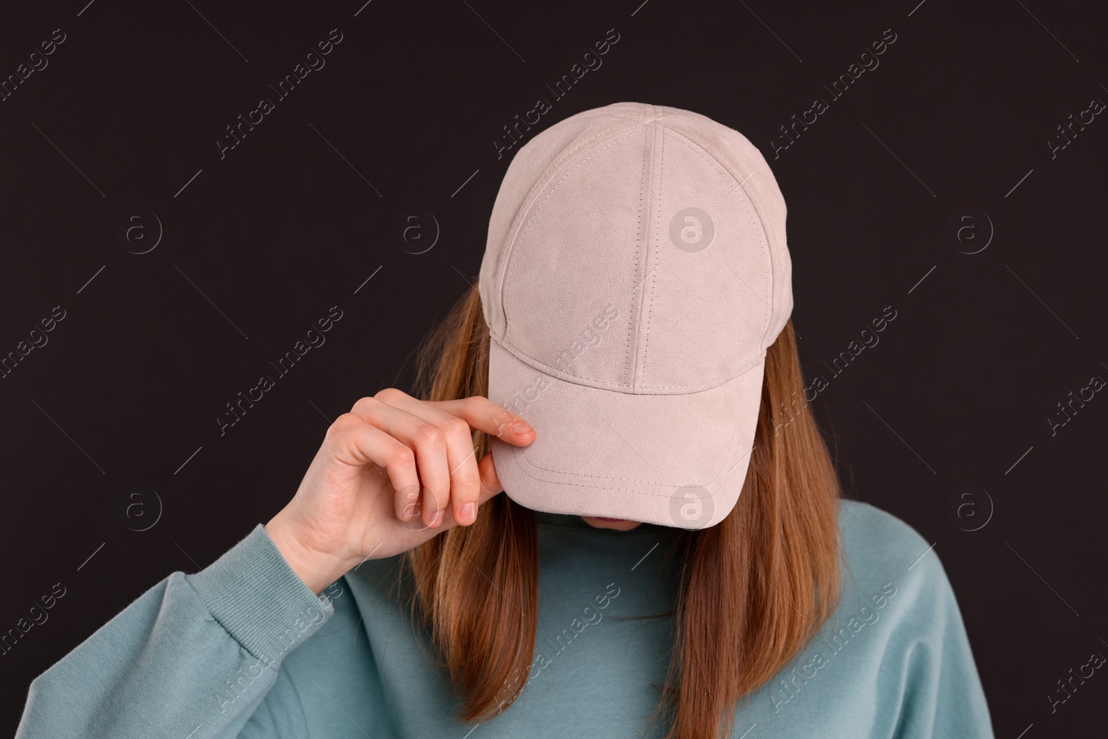 Photo of Woman in stylish baseball cap on black background. Mockup for design