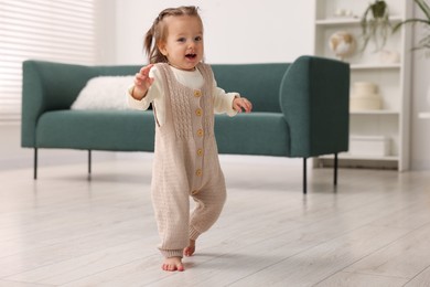 Photo of First steps. Cute little baby learning to walk at home