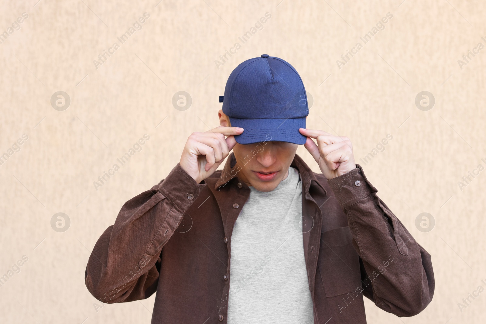 Photo of Man in stylish baseball cap near beige wall. Mockup for design