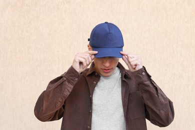 Photo of Man in stylish baseball cap near beige wall. Mockup for design