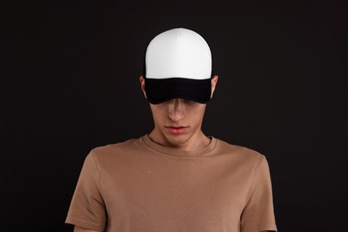 Photo of Man in stylish baseball cap on black background. Mockup for design