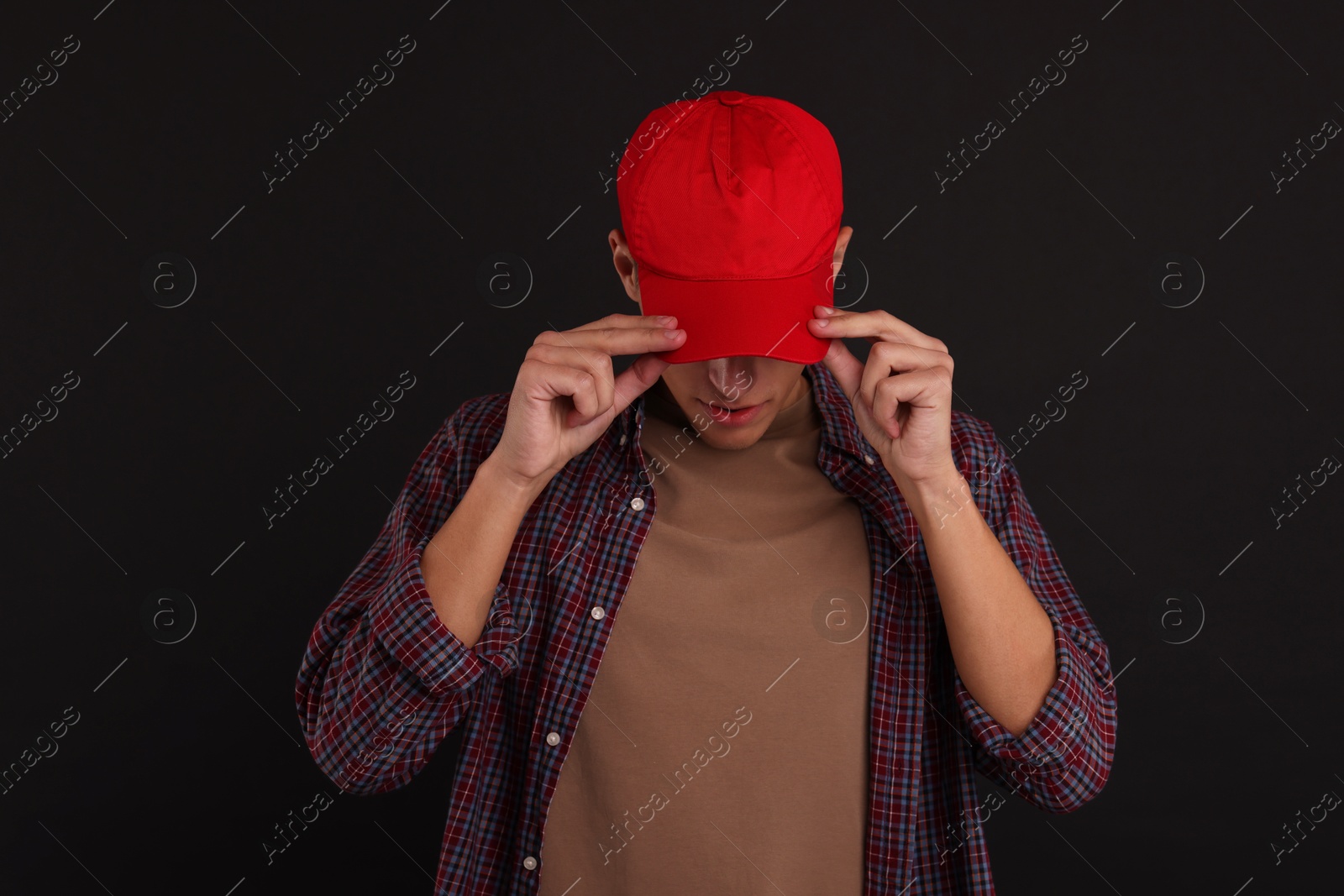 Photo of Man in stylish baseball cap on black background. Mockup for design