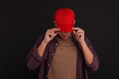 Photo of Man in stylish baseball cap on black background. Mockup for design