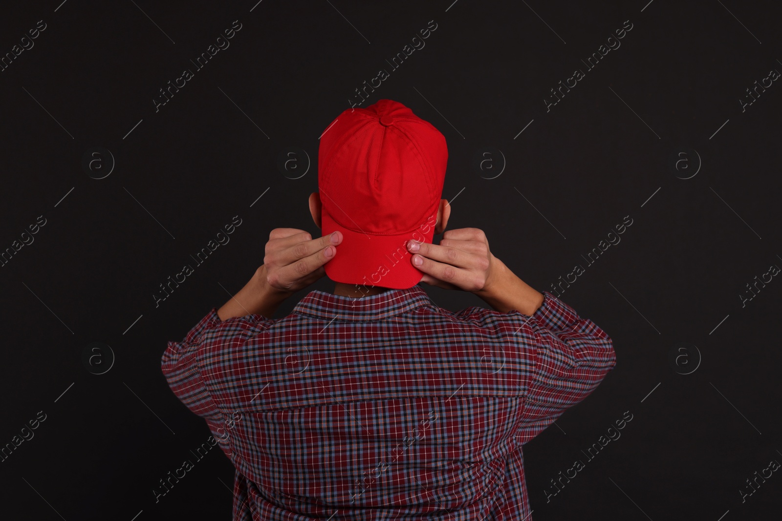 Photo of Man in stylish baseball cap on black background, back view. Mockup for design