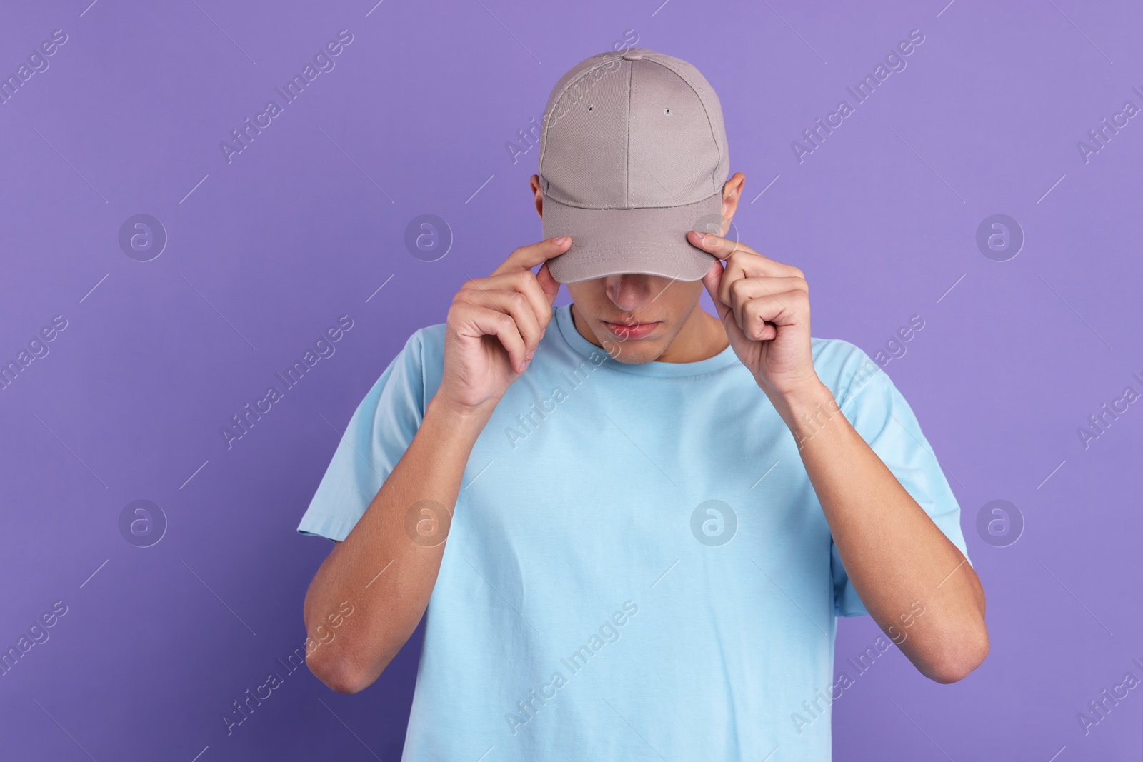 Photo of Man in stylish baseball cap on violet background. Mockup for design