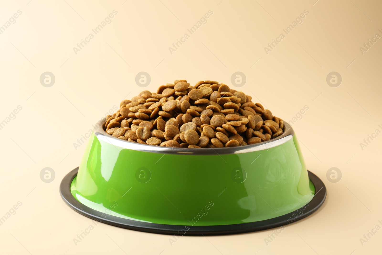 Photo of Dry pet food in feeding bowl on beige background