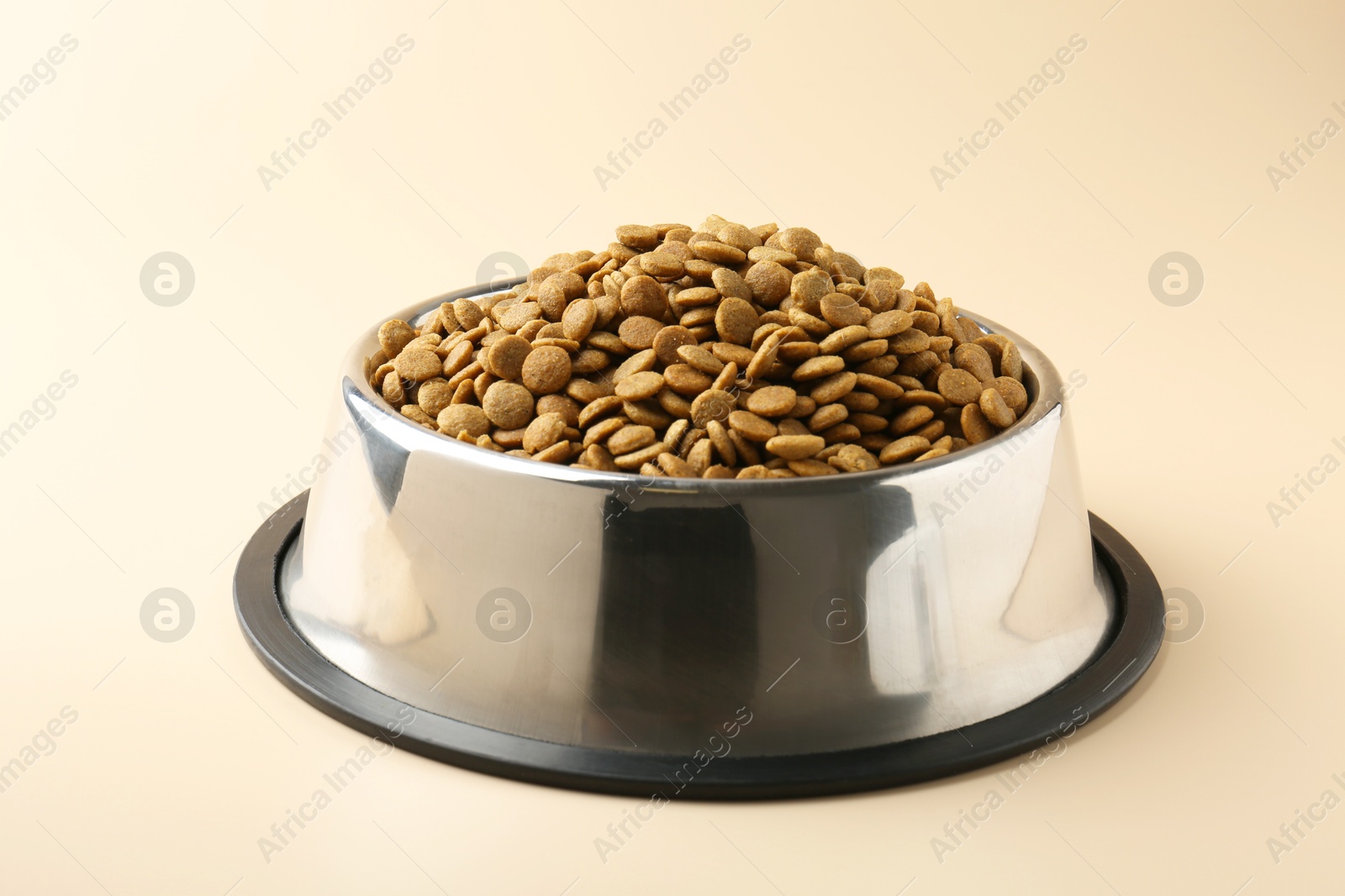 Photo of Dry pet food in feeding bowl on beige background