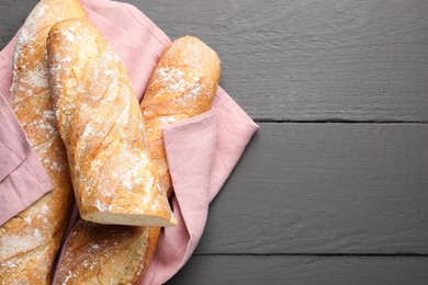 Photo of Cut fresh baguettes on grey wooden table, top view. Space for text