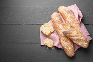 Photo of Cut fresh baguettes on grey wooden table, top view. Space for text