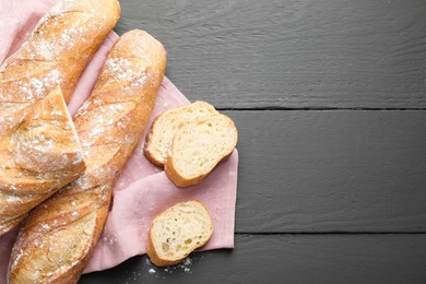 Photo of Cut fresh baguettes on grey wooden table, top view. Space for text